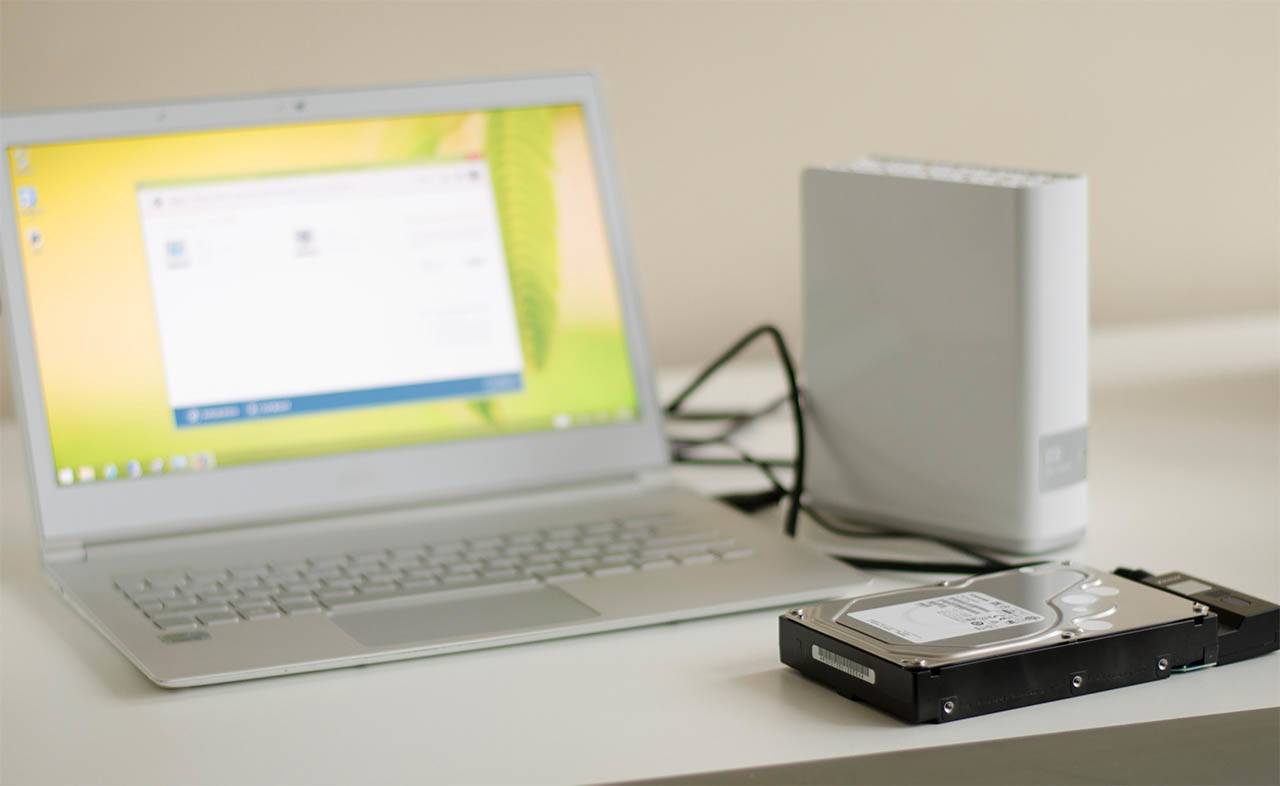 NAS-Gerät und Festplatte neben Laptop